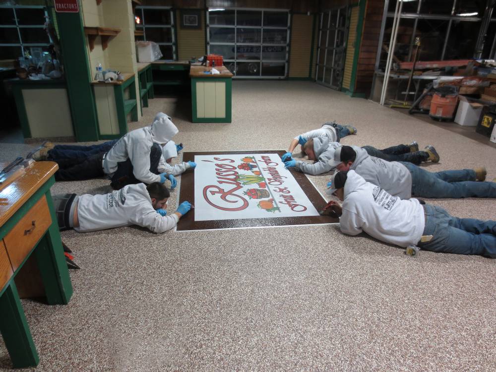 The PermaFloor crew puts the final touches on a custom logo installation.
