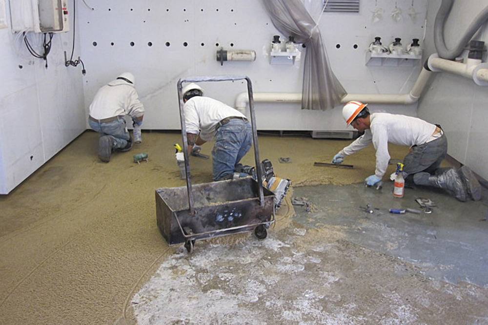 Hand troweling of epoxy mortar around floor protrusions and room edges.